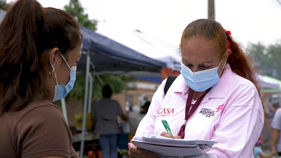A 'promotora' (health promoter) from CASA, a Hispanic advocacy group, tries to enroll Latinos as volunteers to test a potential COVID-19 vaccine, at a farmers market in Takoma Park, Maryland on Sept. 9, 2020. Minority enrollment in studies of two shots has inched up in recent weeks, but even more is needed this fall as additional vaccine testing gets underway over the next two months.