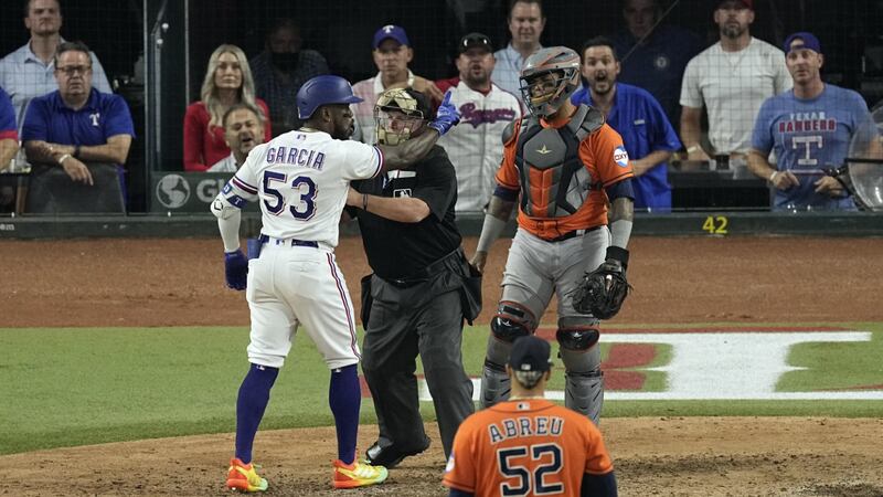 Texas Rangers' Adolis Garcia (53) is restrained by home plate umpire Marvin Hudson as he yells...