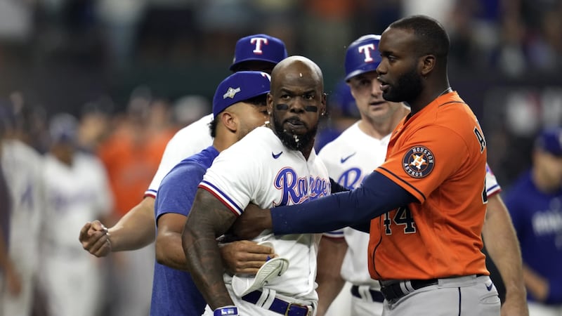 Texas Rangers' Adolis Garcia is restrained by teammates and Houston Astros' Yordan Alvarez...