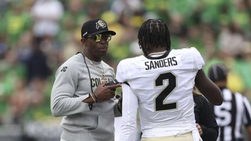 Colorado head coach Deion Sanders talks with his son and quarterback Shedeur Sanders during...