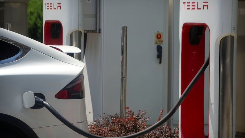 A vehicle charges at an electric vehicle charging station outside of a Tesla dealership in...