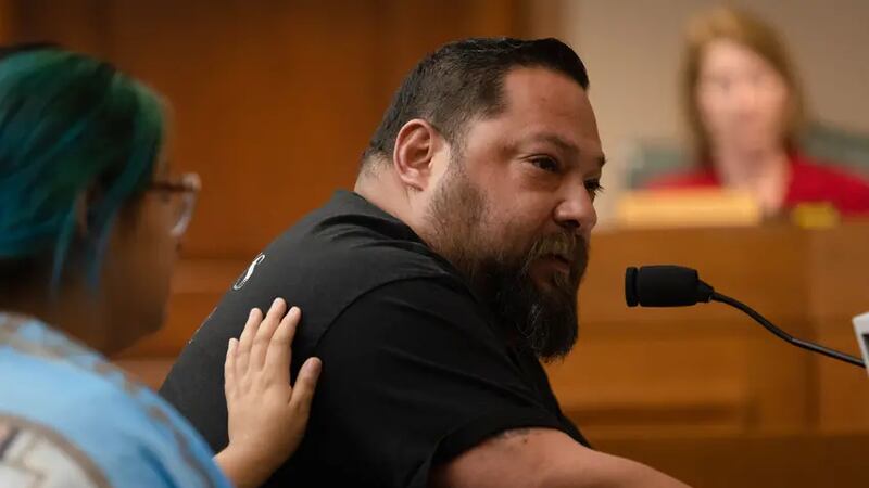 Jasmine Cazares places a hand on her father, Javier, to console him, while he speaks through...