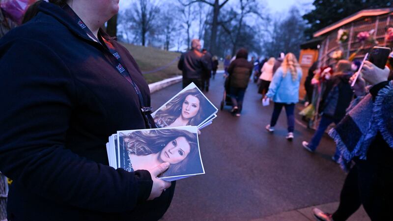 An attendant holds programs as fans enter Graceland for a memorial service for Lisa Marie...