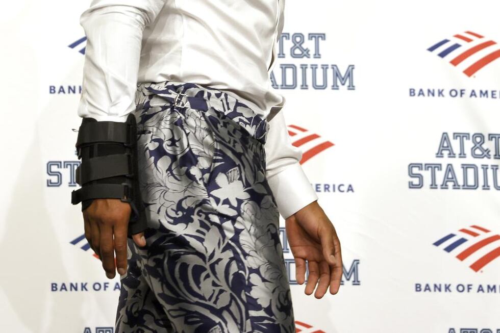 Dallas Cowboys quarterback Dak Prescott, wearing a brace on his right hand, walks away from...